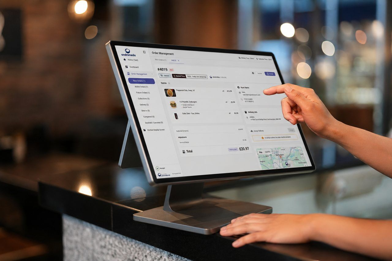 Andromeda POS in use behind the counter — order taking, kitchen tickets and live delivery on one platform